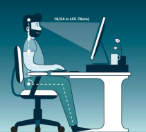 A person sat ergonomically at a desk with their monitor at eye level and arms at 90 degrees. The desk includes a mug and a small plant.